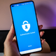 A photo of a person holding up an Android phone with the Authenticator app on screen